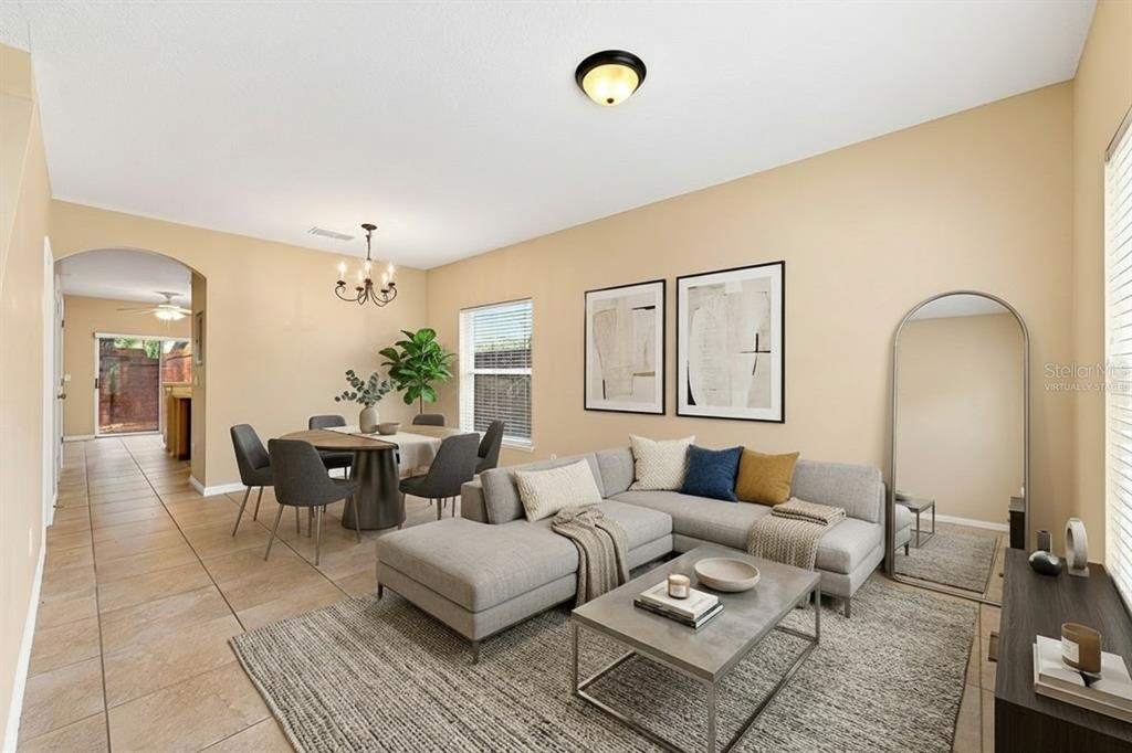 A living and dining room with tile floors, a gray sectional sofa, and a dining table — 102 WILTON CIRCLE, SANFORD, FL
