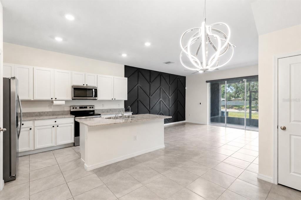 A kitchen with white cabinets, granite countertops, and a black accent wall with geometric molding — 34347 SORREL MINT DRIVE, WESLEY CHAPEL, FL