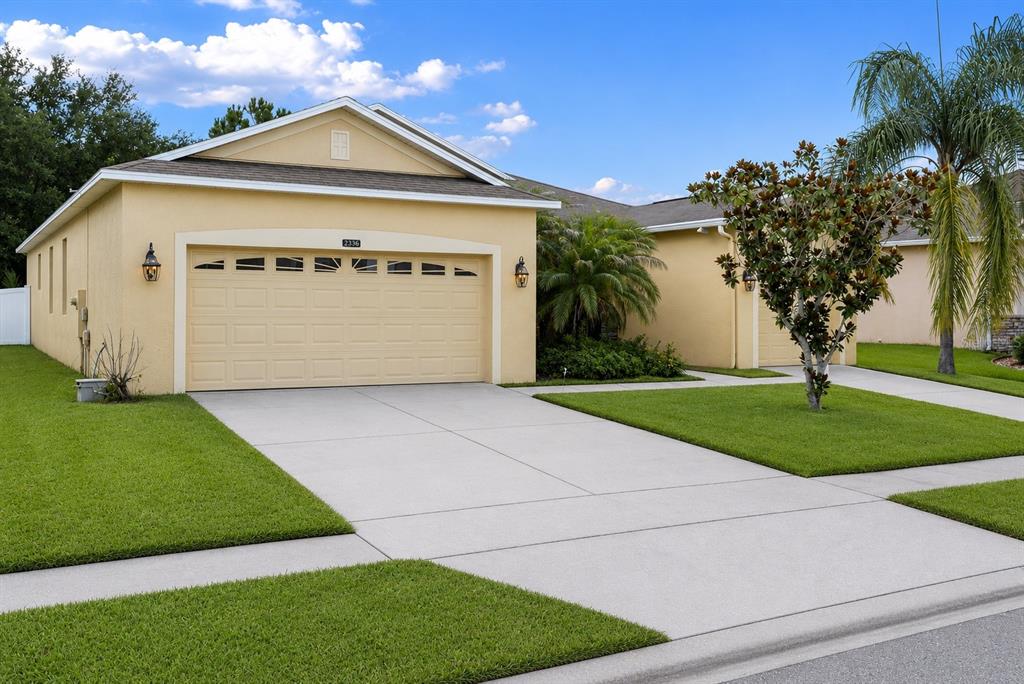 A yellow single-story house with a two-car garage and a concrete driveway — 2336 CROSSTON CIRCLE, ORLANDO, FL