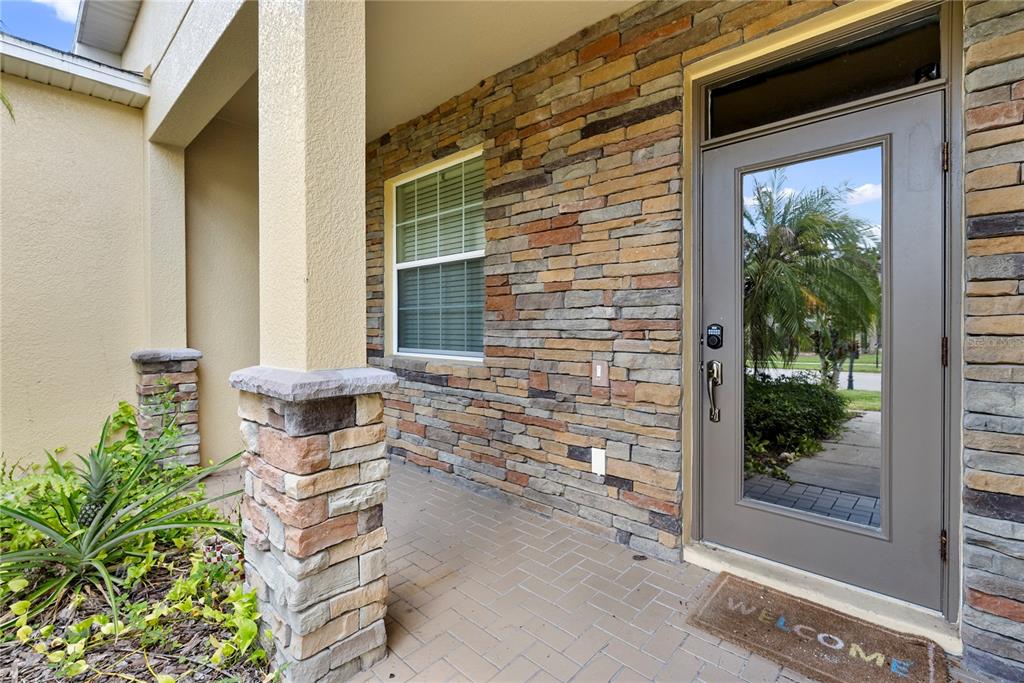 A front porch features a stone-veneer wall, a glass-paneled door, and a brick-paver floor — 2336 CROSSTON CIRCLE, ORLANDO, FL