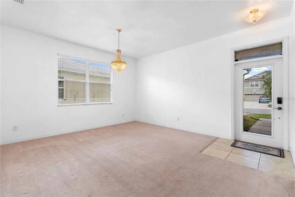 An empty dining room features beige carpeting, a crystal chandelier, and a glass-paneled front door — 2336 CROSSTON CIRCLE, ORLANDO, FL