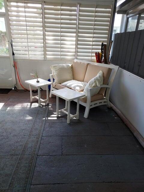 A sunroom features a white loveseat, two small side tables, and a patterned area rug — 9417 S Ocean Drive # 37, Jensen Beach FL 34957, JENSEN BEACH, FL