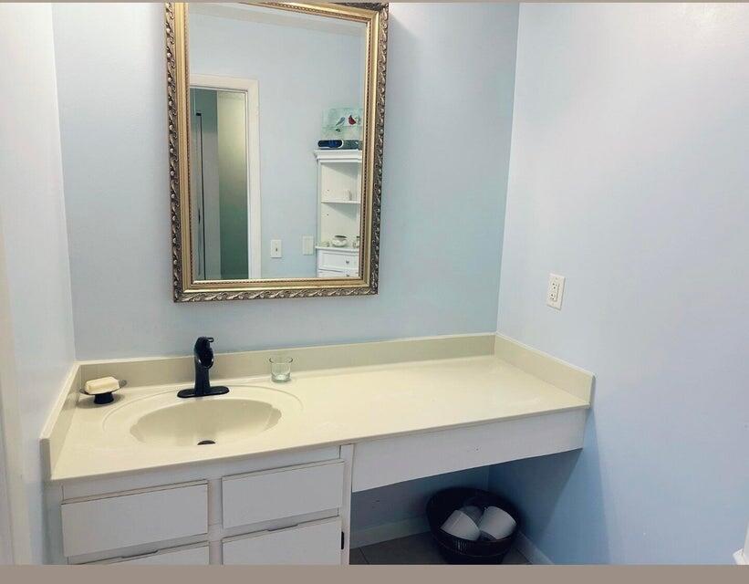 A bathroom vanity with a single sink, black faucet, and gold-framed mirror against blue walls — 9417 S Ocean Drive # 37, Jensen Beach FL 34957, JENSEN BEACH, FL
