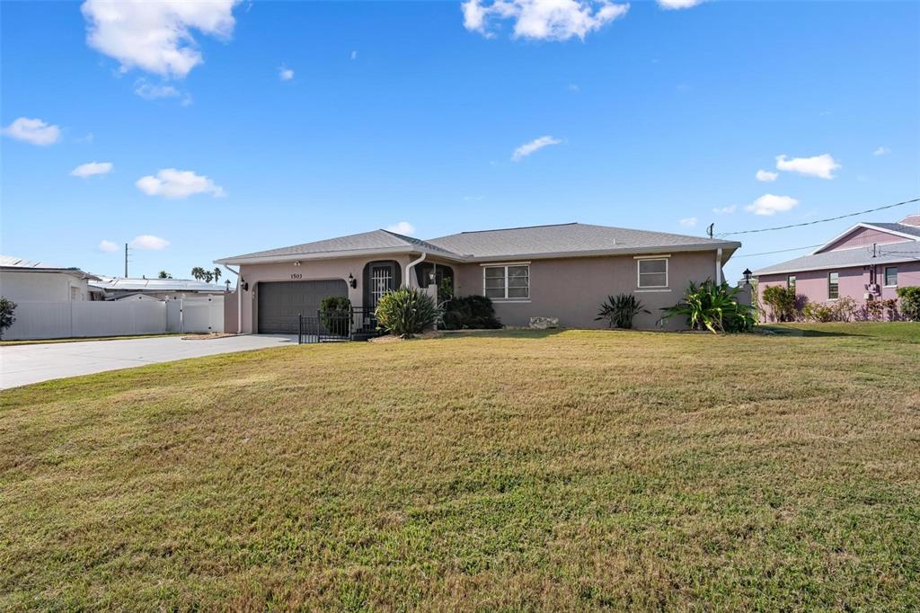 A single-story house with a gray roof, tan exterior, and a large front lawn — 1503 MARLIN STREET, NOKOMIS, FL