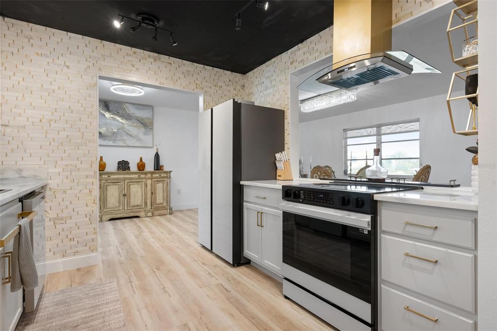 A modern kitchen features light wood flooring, white cabinetry, a black ceiling, and a range hood — 1503 MARLIN STREET, NOKOMIS, FL