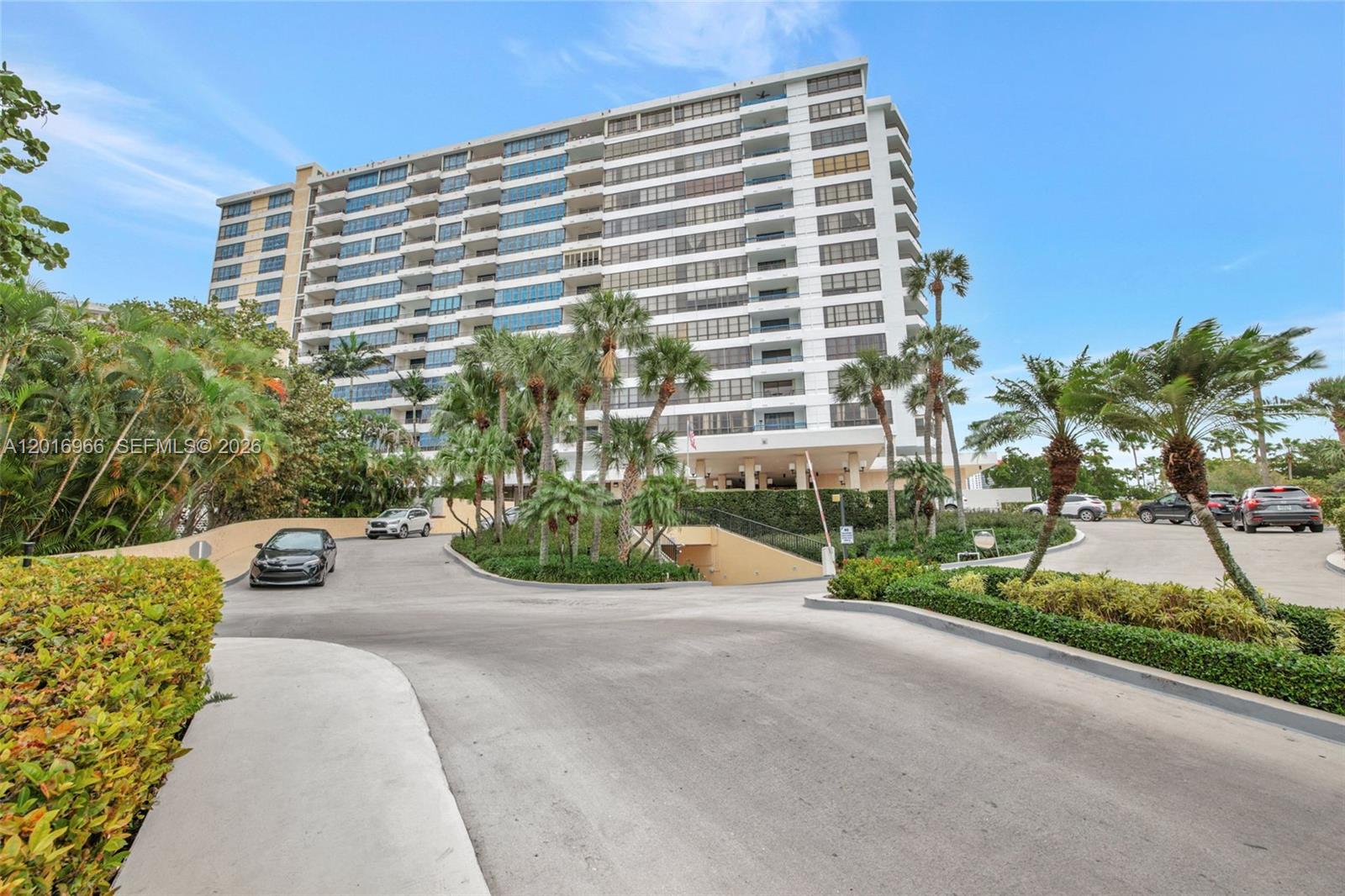 A multi-story residential building features a paved driveway, palm trees, and parked cars — 500 Three Islands Blvd # 622, Hallandale Beach FL 33009, HALLANDALE BEACH, FL
