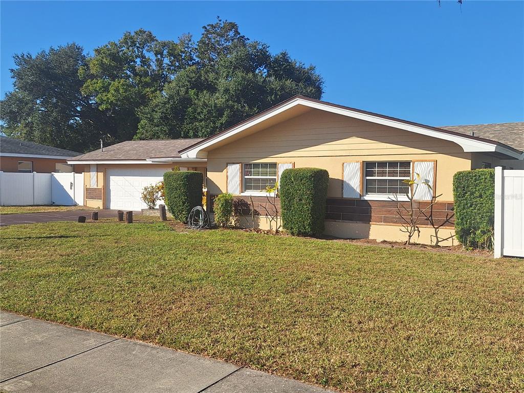 A single-story house with a tan exterior, a two-car garage, and manicured hedges — 1202 S KEENE ROAD, CLEARWATER, FL