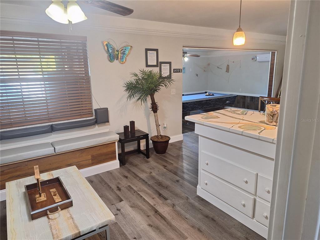 A living area with built-in seating and a tiled island opens into a pool room — 1202 S KEENE ROAD, CLEARWATER, FL