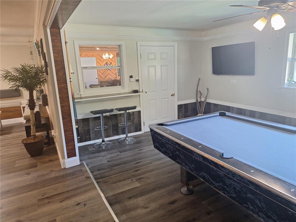 A game room features a pool table, a breakfast bar with stools, and wood-look flooring — 1202 S KEENE ROAD, CLEARWATER, FL