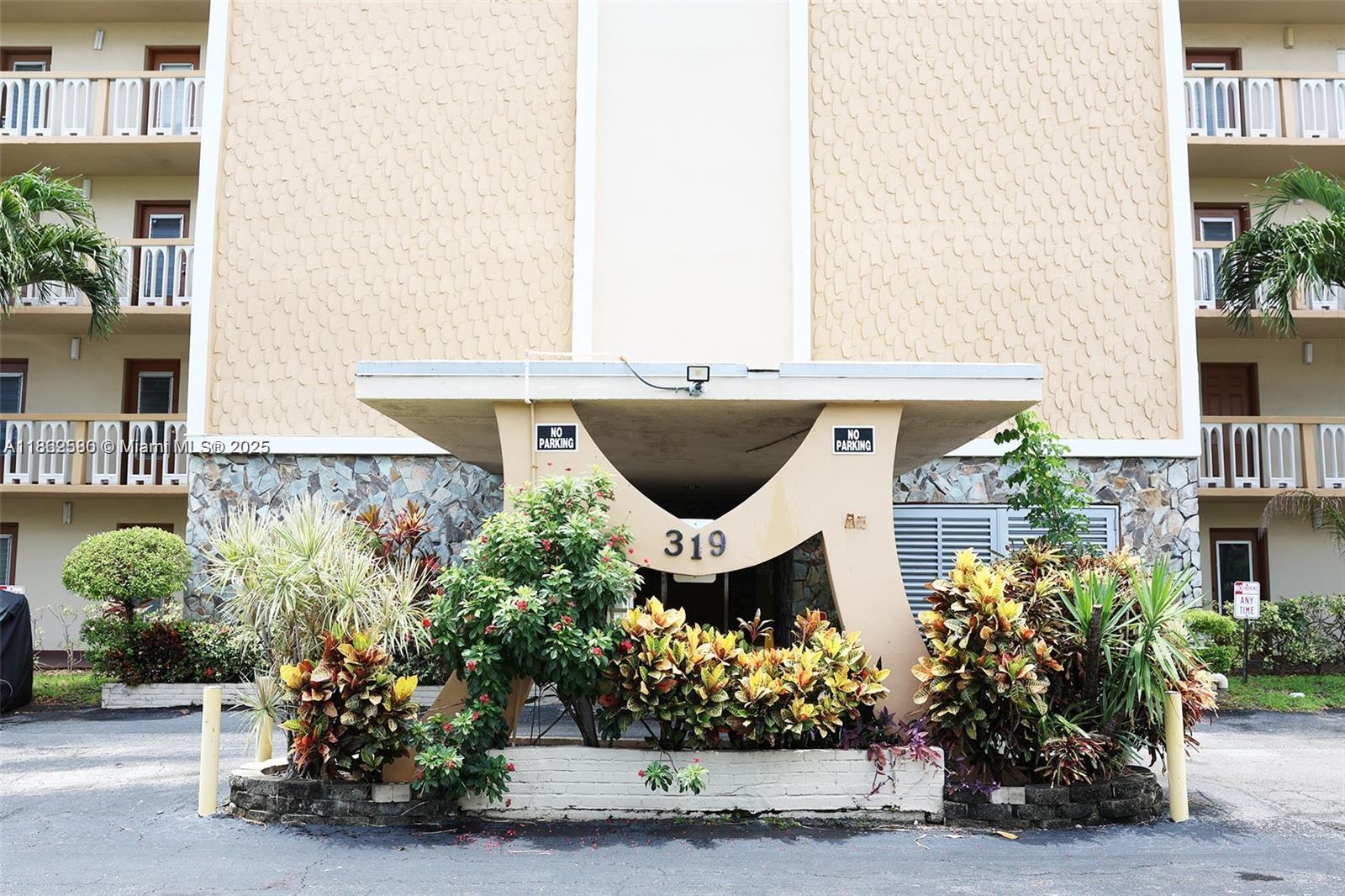 The exterior of a multi-story apartment building features a covered entrance marked with the number 319 — 319 NE 14th Ave # 505, Hallandale Beach FL 33009, HALLANDALE BEACH, FL