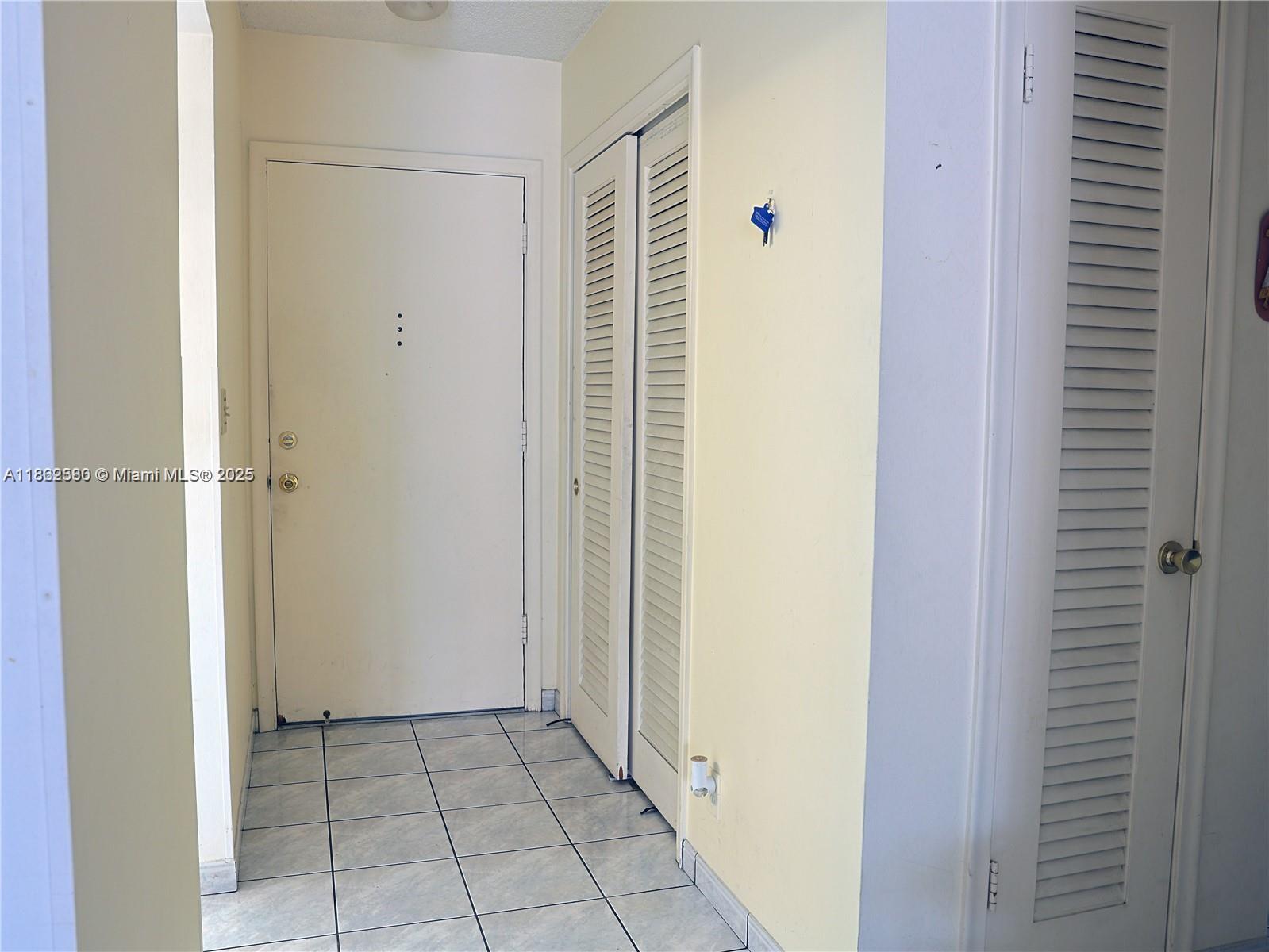 An entryway features a white door, louvered closet doors, and light-colored tile flooring — 319 NE 14th Ave # 505, Hallandale Beach FL 33009, HALLANDALE BEACH, FL