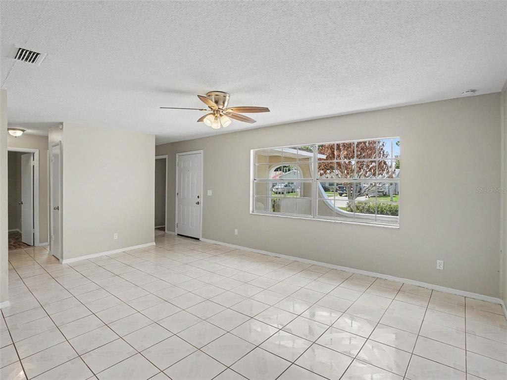 A bright living room with white tile floors, a ceiling fan, and a large window — 615 THOMAS JEFFERSON WAY, ORLANDO, FL