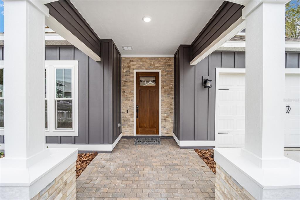 A covered entryway features a brick-paved path, a wooden front door, and dark vertical siding — 893 NW 132ND BOULEVARD, NEWBERRY, FL