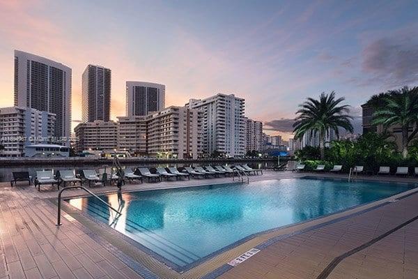 A swimming pool sits on a patio overlooking a city skyline at sunset — 2602 E Hallandale Beach Blvd # R1507, Hallandale Beach FL 33009, HALLANDALE BEACH, FL