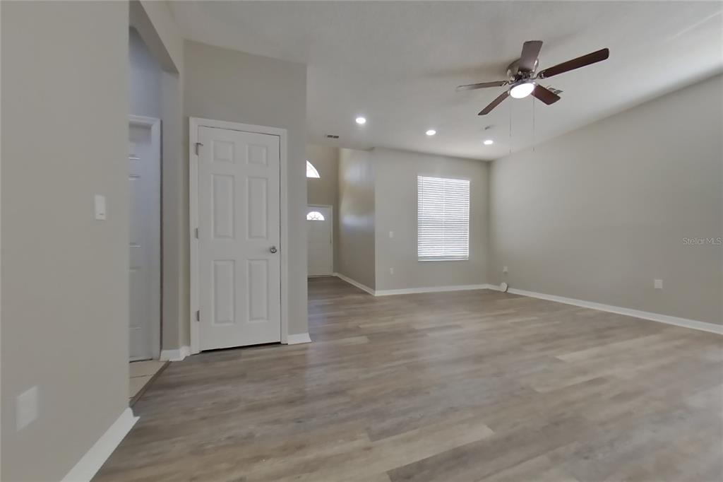 A living room features light gray walls, wood-look flooring, a ceiling fan, and white doors — 408 E IDLEWILD AVENUE, EUSTIS, FL