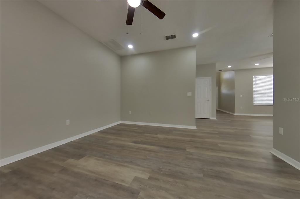 An empty room features light-colored walls, wood-look flooring, and a ceiling fan — 408 E IDLEWILD AVENUE, EUSTIS, FL