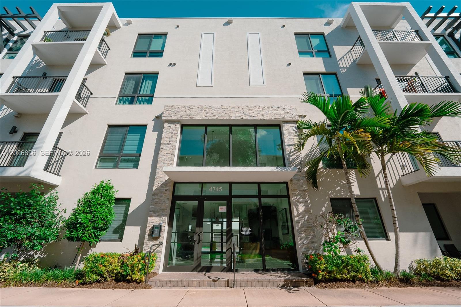 A low-angle exterior view of a modern multi-story apartment building with a glass entrance — 4745 NW 84th Ct # 47, Doral FL 33166, DORAL, FL