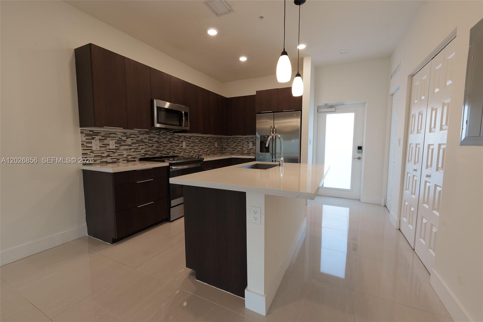A modern kitchen features dark wood cabinets, stainless steel appliances, and a white quartz island — 4745 NW 84th Ct # 47, Doral FL 33166, DORAL, FL