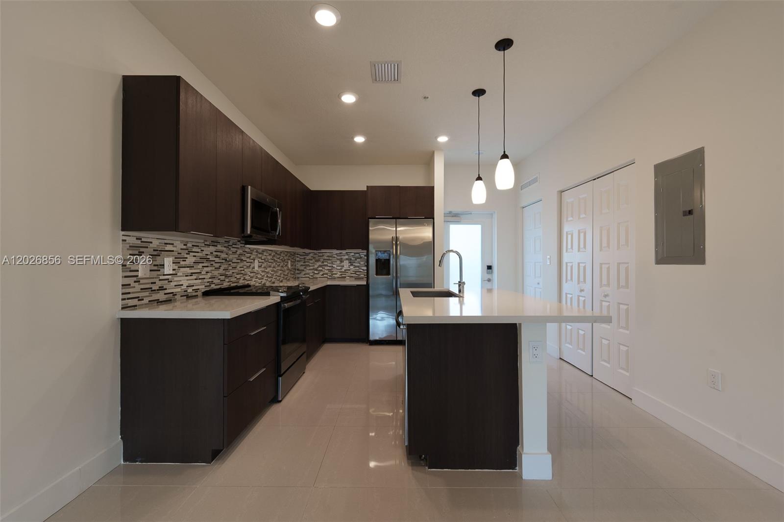 A modern kitchen features dark wood cabinets, white countertops, stainless steel appliances, and tile flooring — 4745 NW 84th Ct # 47, Doral FL 33166, DORAL, FL