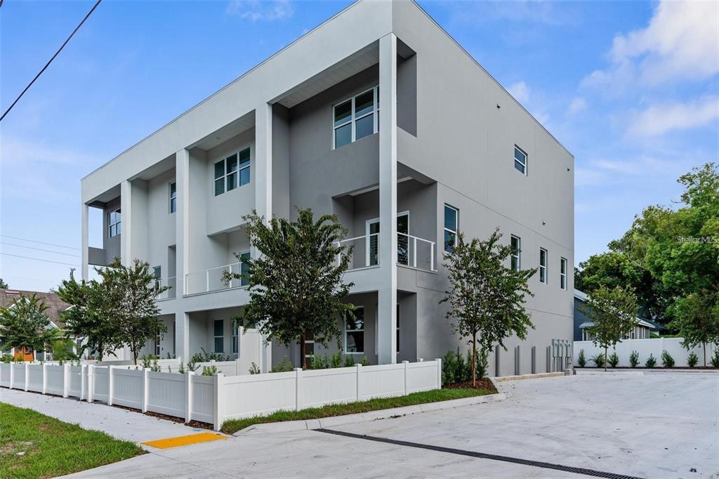 A modern three-story townhouse with a white fence and a concrete driveway — 102 W ADALEE STREET UNIT 3, TAMPA, FL