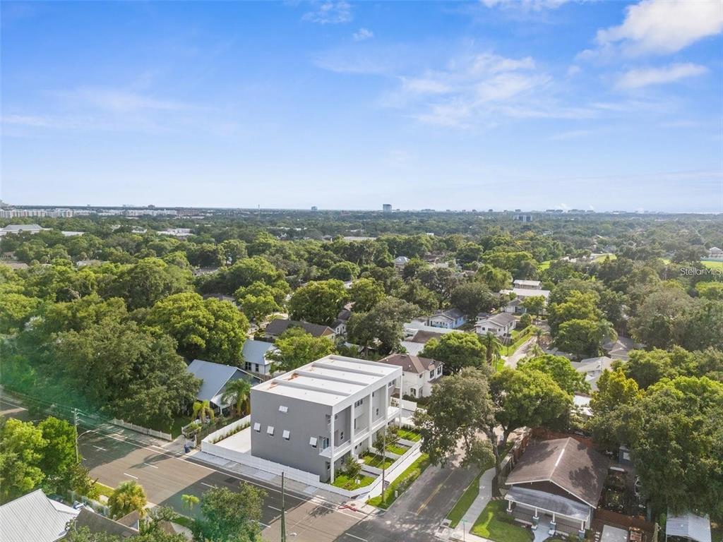 An aerial view shows a modern gray multi-unit building situated in a tree-filled neighborhood — 102 W ADALEE STREET UNIT 3, TAMPA, FL