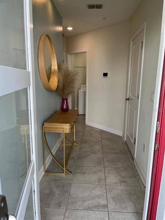 An entryway features a console table, a round mirror, and a view toward a laundry room — 563 OCEAN COURSE AVENUE UNIT N/A, DAVENPORT, FL