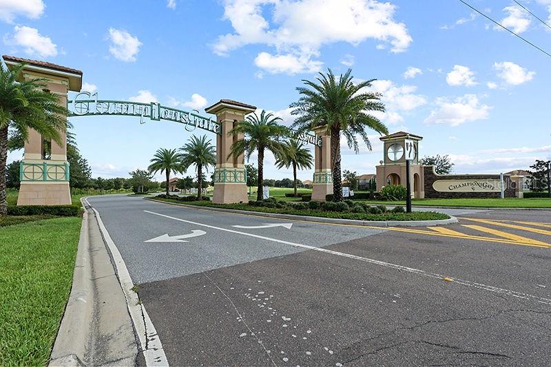 A large stone archway marks the entrance to the ChampionsGate community with palm trees — 563 OCEAN COURSE AVENUE UNIT N/A, DAVENPORT, FL