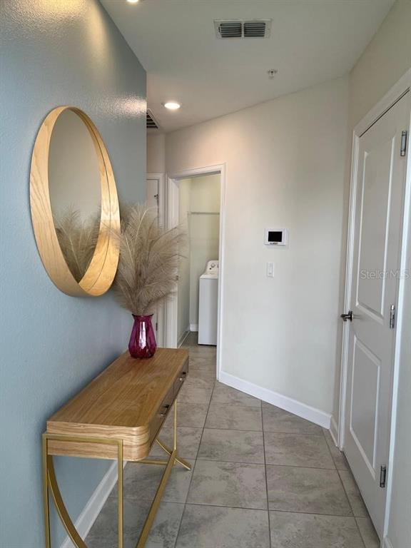 A hallway features a wooden console table, a round mirror, and a doorway to a laundry — 563 OCEAN COURSE AVENUE UNIT N/A, DAVENPORT, FL