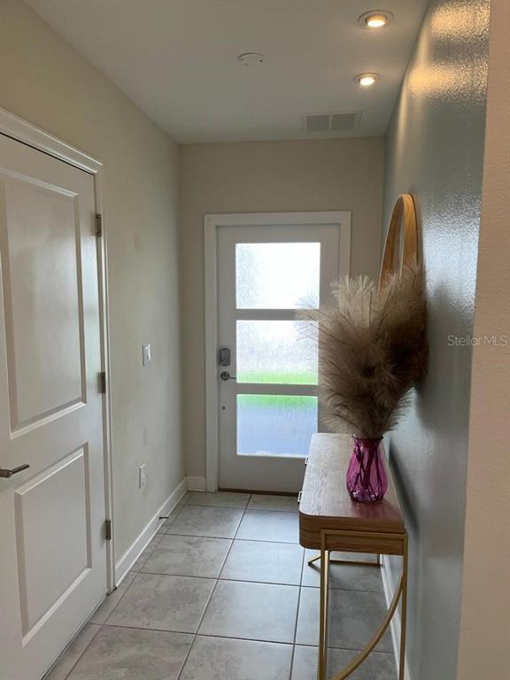 An entryway features a tiled floor, a console table with a vase, and a door — 563 OCEAN COURSE AVENUE UNIT N/A, DAVENPORT, FL