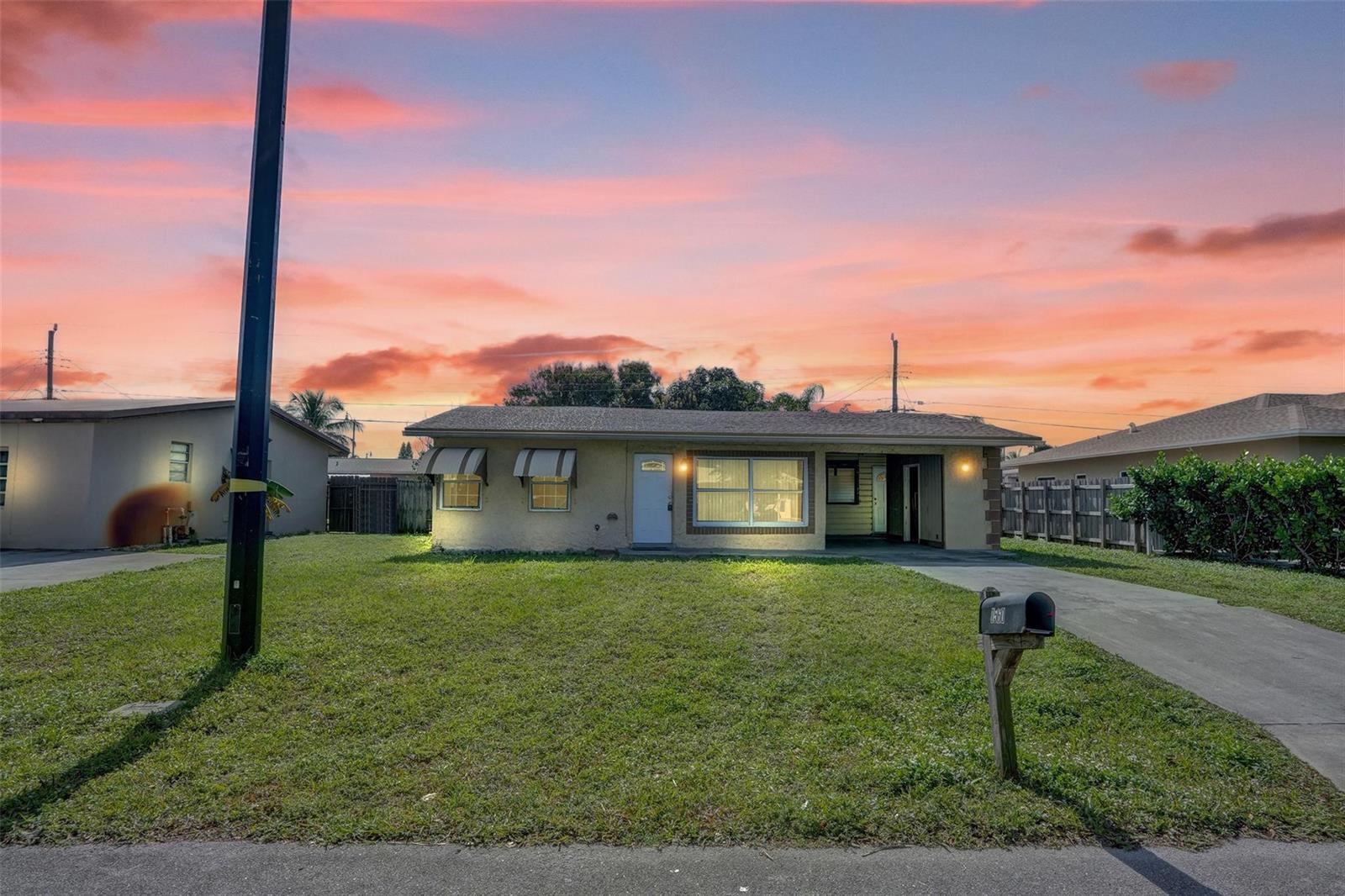 A single-story house with a lawn, driveway, and mailbox under a sunset sky — 1560 NE 31st Court, Pompano Beach FL 33064, POMPANO BEACH, FL