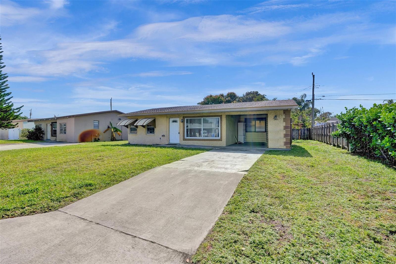 A single-story house with a concrete driveway, a carport, and a grassy front yard — 1560 NE 31st Court, Pompano Beach FL 33064, POMPANO BEACH, FL