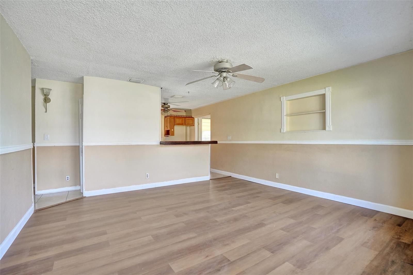 An empty living room features wood-look flooring, two-tone walls, a ceiling fan, and a pass-through — 1560 NE 31st Court, Pompano Beach FL 33064, POMPANO BEACH, FL