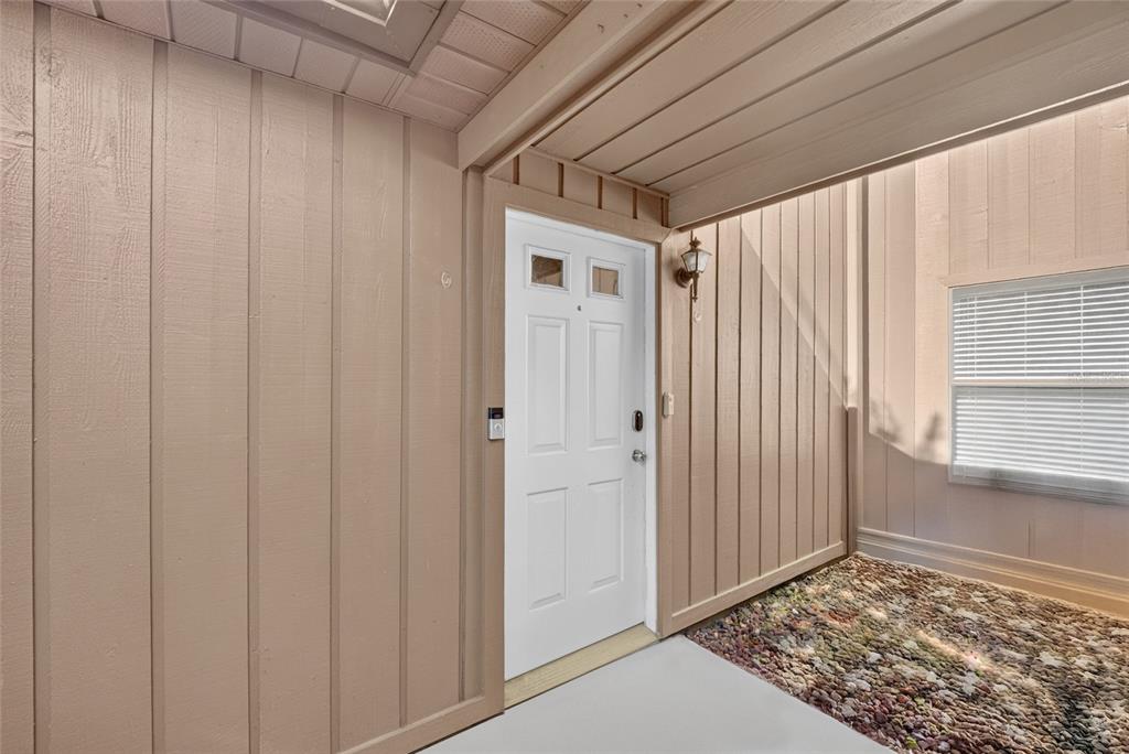 A white front door with two small windows is set within a beige-sided entryway — 2701 NE 10TH STREET UNIT 603, OCALA, FL