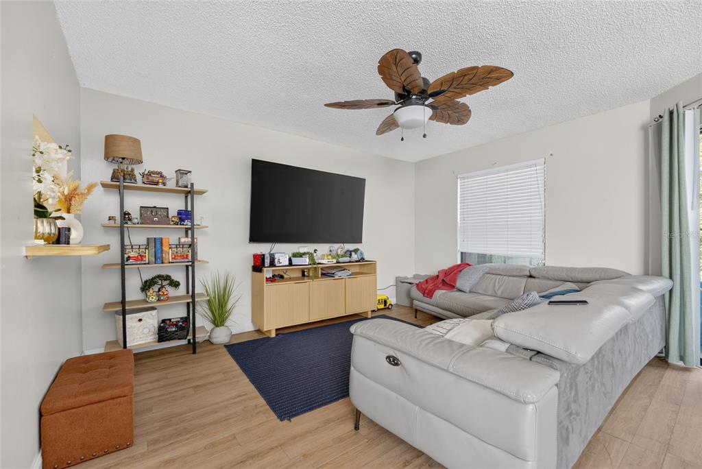 A living room features a sectional sofa, a television on a console, and a ceiling fan — 2701 NE 10TH STREET UNIT 603, OCALA, FL