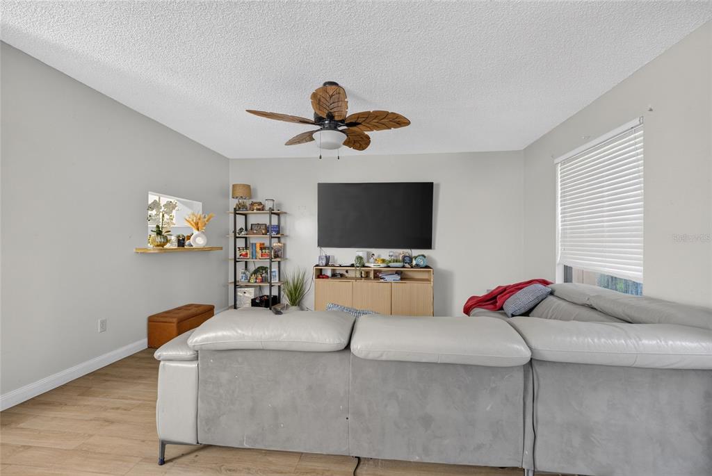 A living room features a grey sectional sofa, a wall-mounted television, and a ceiling fan — 2701 NE 10TH STREET UNIT 603, OCALA, FL