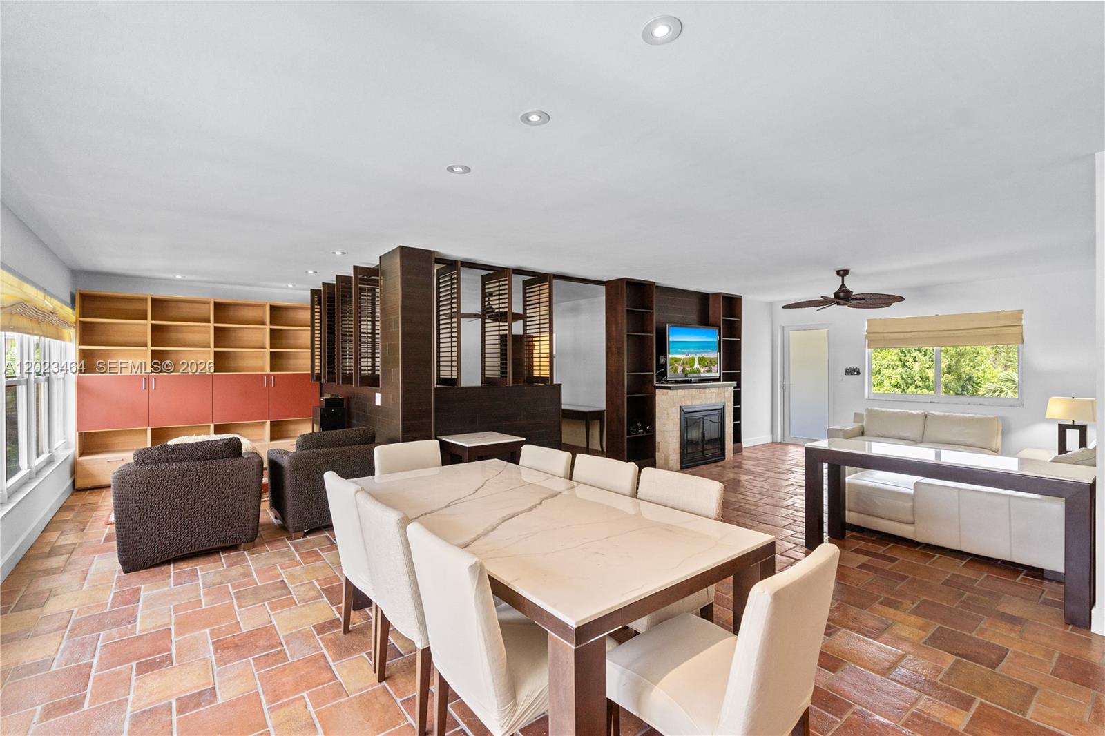 A dining and living area features terracotta tile floors, a fireplace, and built-in shelving — 10190 Collins Ave, Bal Harbour FL 33154, BAL HARBOUR, FL