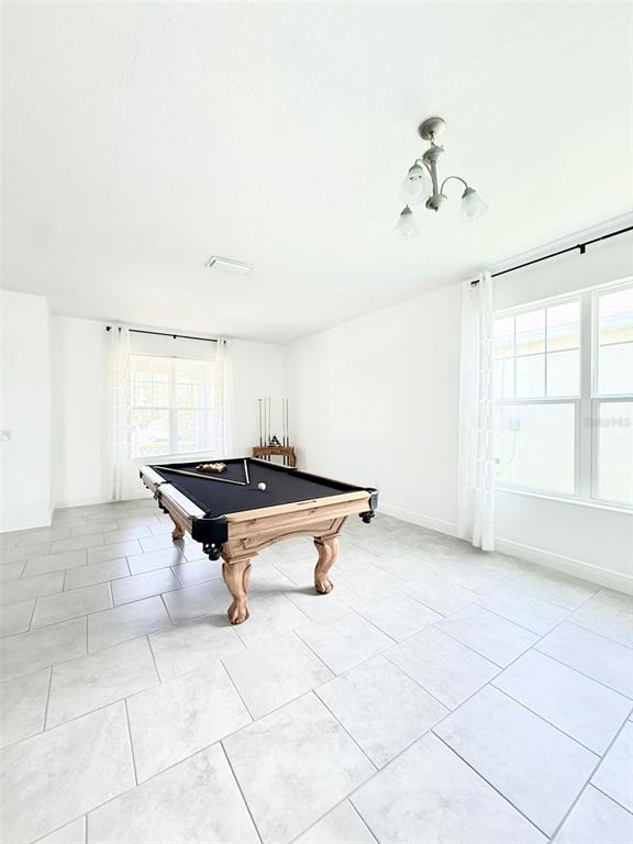 A bright room features a pool table, light tile flooring, and a modern light fixture — 2993 NOTTEL DRIVE, ST CLOUD, FL