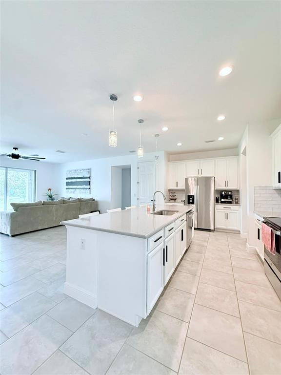 A kitchen with white cabinets and a large island overlooks an open-concept living area — 2993 NOTTEL DRIVE, ST CLOUD, FL