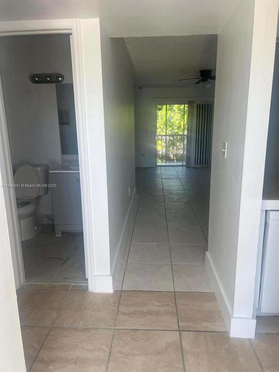 A tiled hallway leads from a bathroom toward a living area with a sliding glass door — 438 NE 210th Cir Ter # 4B, Miami FL 33179, MIAMI, FL