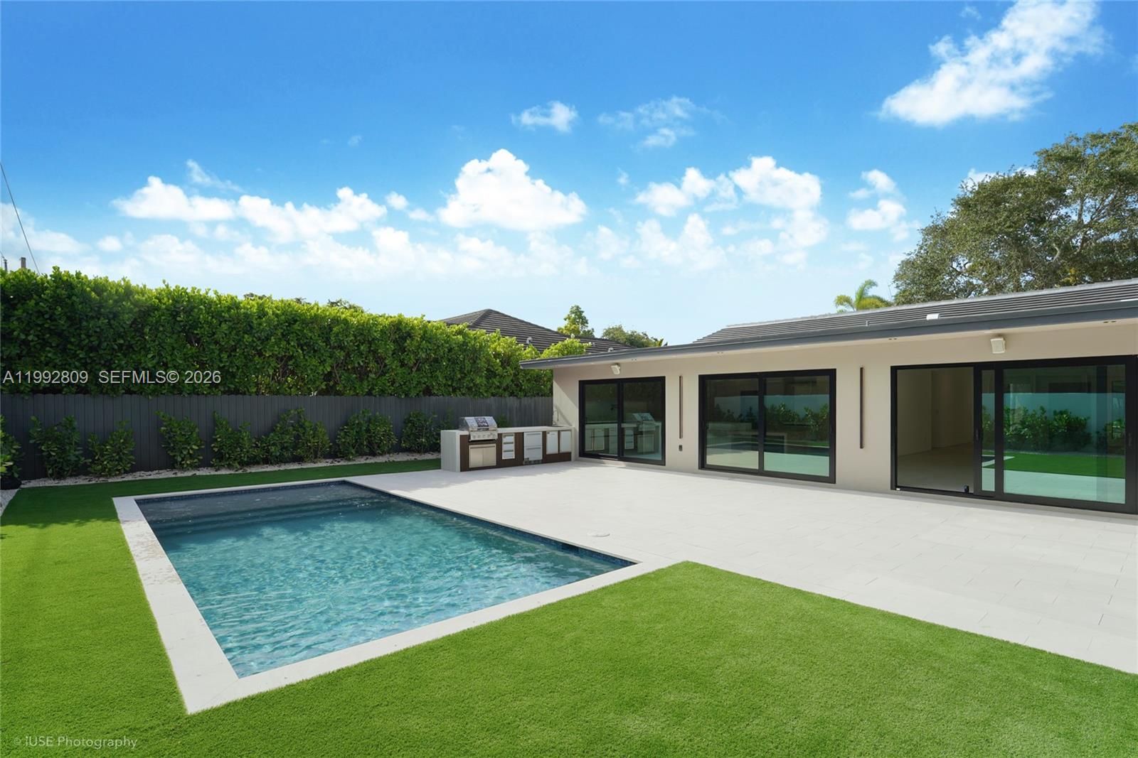 A backyard features a swimming pool, a paved patio, and an outdoor kitchen area — 21490 Highland Lakes Blvd, Miami FL 33179, MIAMI, FL