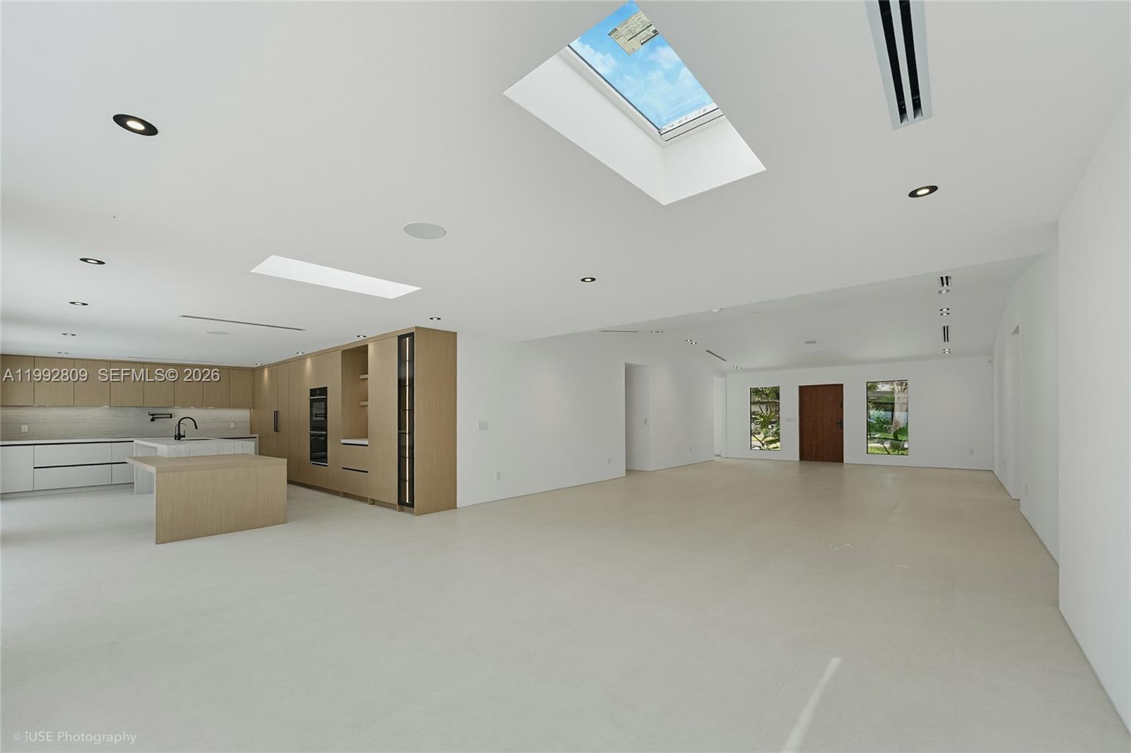 A modern, open-concept kitchen and living area features white walls, light wood cabinetry, and skylights — 21490 Highland Lakes Blvd, Miami FL 33179, MIAMI, FL