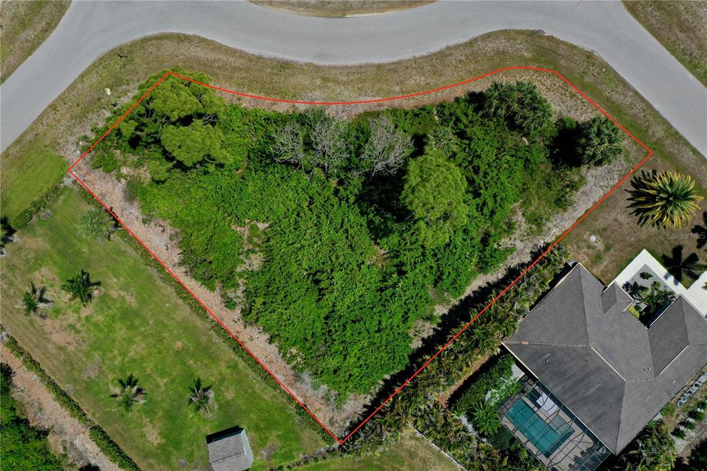 An aerial view shows a vacant, wooded residential lot outlined in red along a curved road — 125 AUSTRALIAN DRIVE, ROTONDA WEST, FL