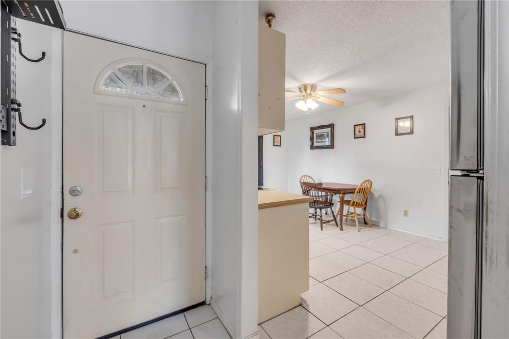 A white front door opens into a dining area with tile floors and a ceiling fan — 2509 WOODLAND DRIVE, EDGEWATER, FL