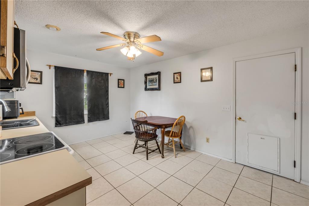 A kitchen with tile flooring, a dining table, and a white door with a pet door — 2509 WOODLAND DRIVE, EDGEWATER, FL