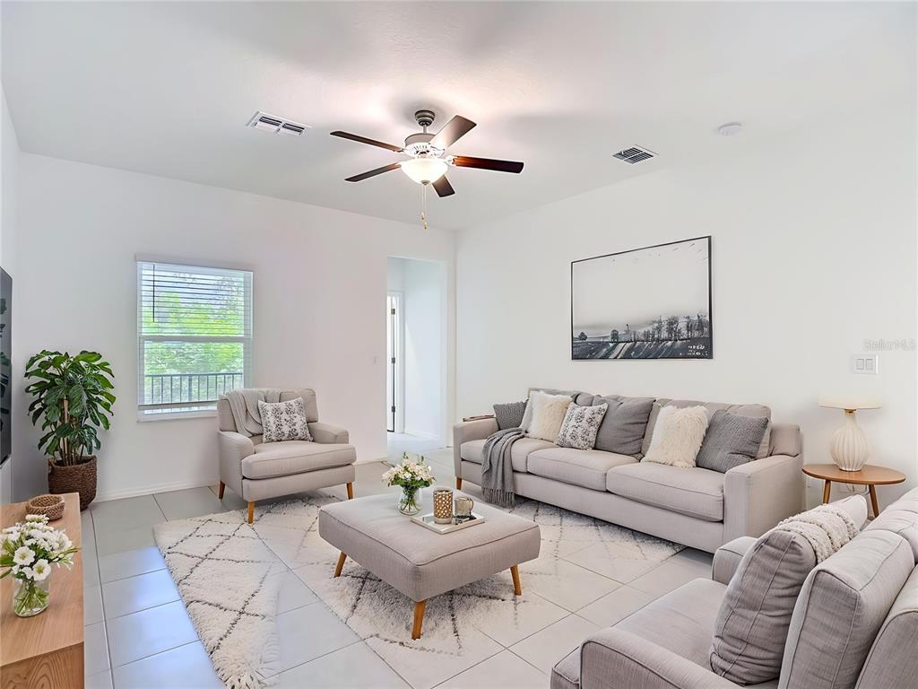 A bright living room features a light gray sofa, matching armchair, ottoman, and tiled floors — 840 TENNYSON MILL CIRCLE, TAMPA, FL