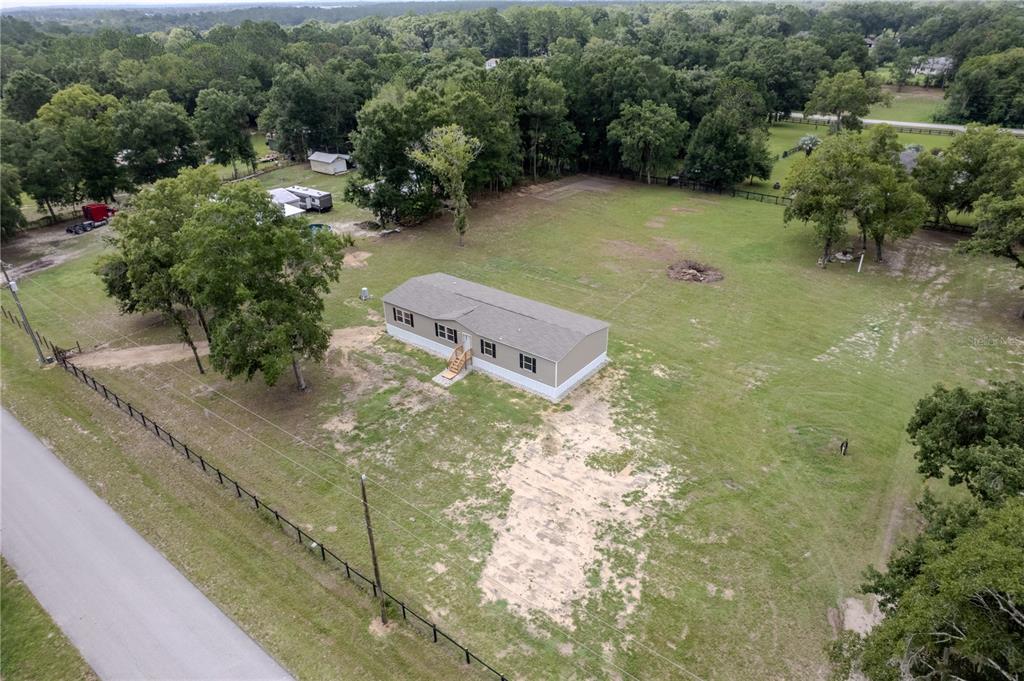 An aerial view shows a manufactured home situated on a large, grassy, tree-lined lot — 7250 SW 10TH STREET, OCALA, FL