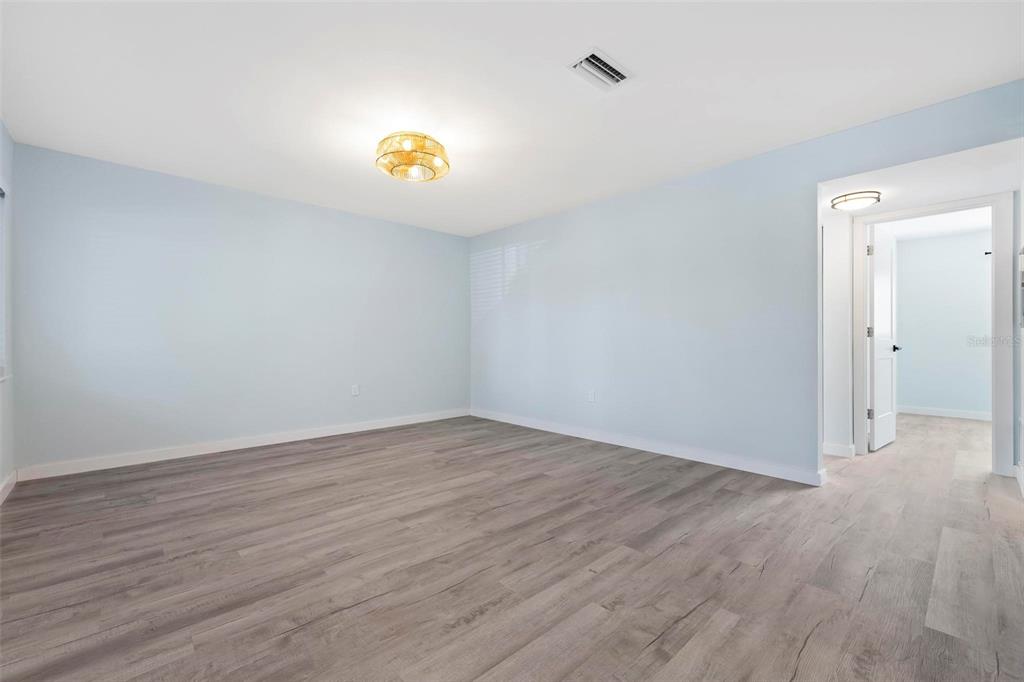 An empty room with light blue walls, wood-look flooring, and a central ceiling light fixture — 1258 BARBARA DRIVE UNIT 107, VENICE, FL