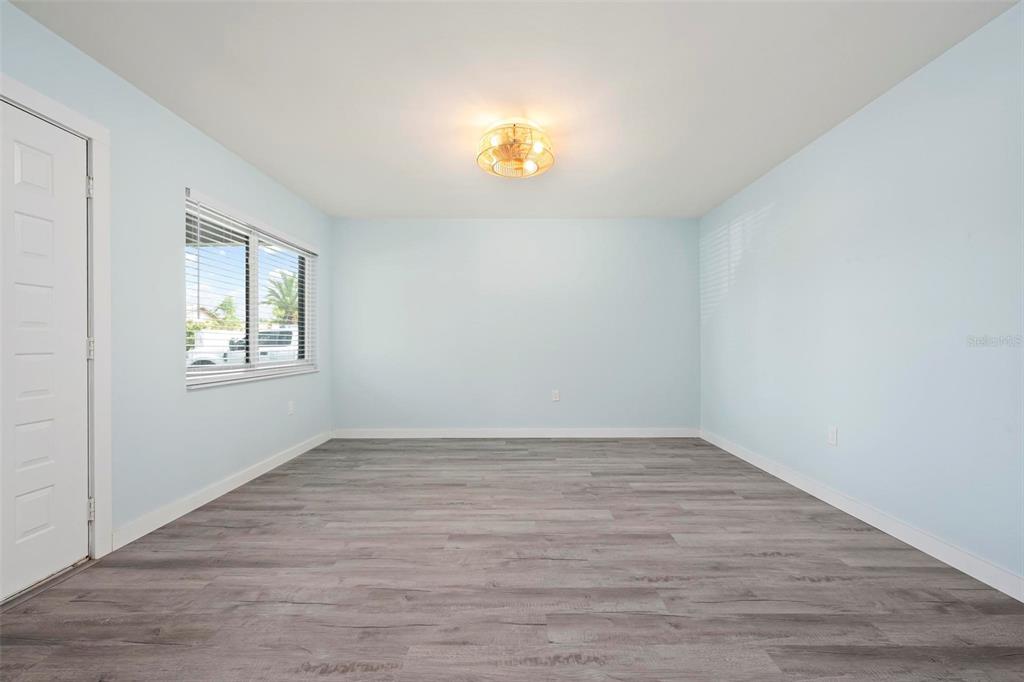 An empty room with light blue walls, gray wood-look flooring, and a ceiling light fixture — 1258 BARBARA DRIVE UNIT 107, VENICE, FL