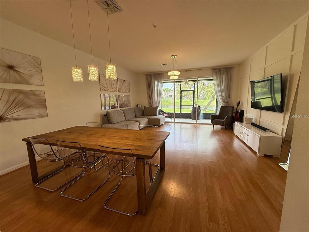 A living and dining area features wood flooring, a large wooden table, and sliding glass doors — 6235 GOETHE STREET UNIT 106, ORLANDO, FL