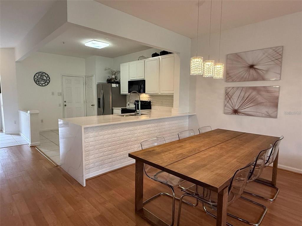 A dining area with a wooden table and clear chairs sits beside a white kitchen — 6235 GOETHE STREET UNIT 106, ORLANDO, FL